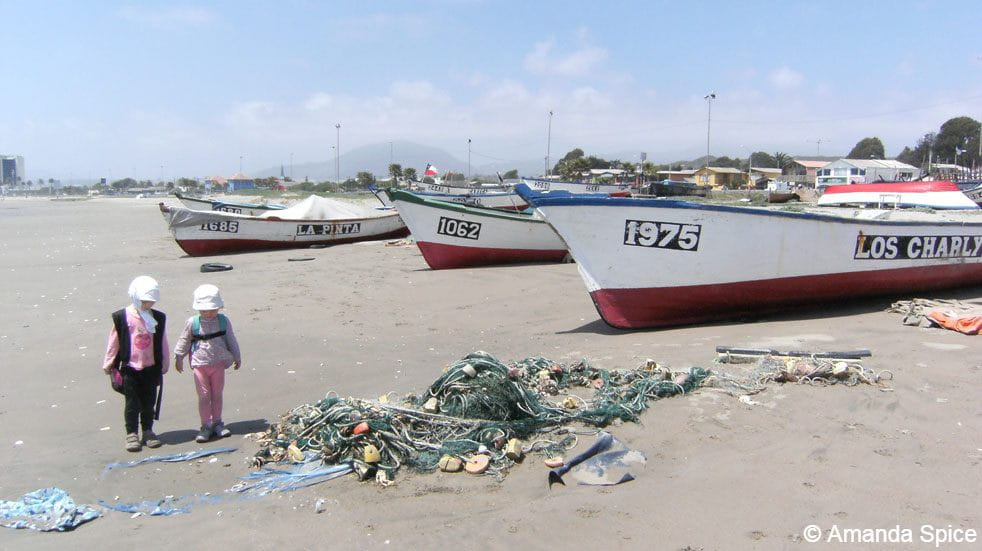 Backpacking with kids; walking onb the beach with boats